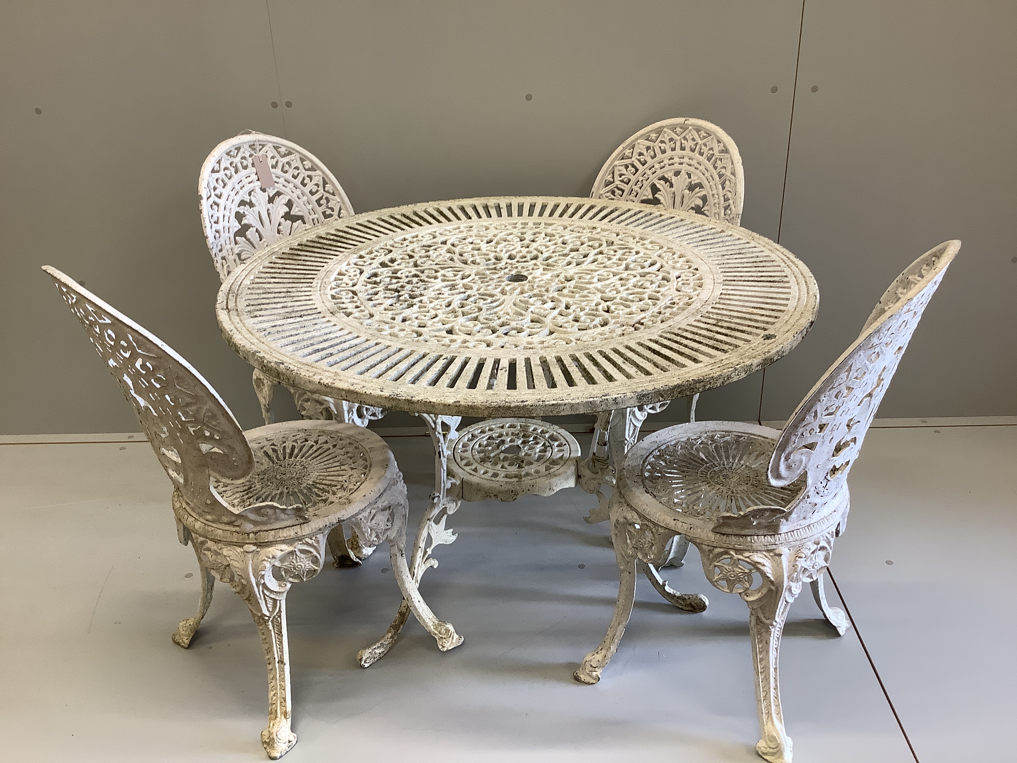 A Victorian style painted cast aluminium circular garden table, diameter 106cm, height 70cm, together with four matching chairs (table, one leg a.f.)